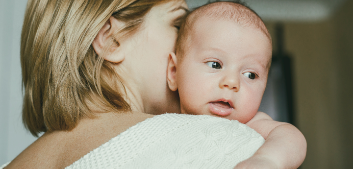 A woman with her back to the camera holding her baby