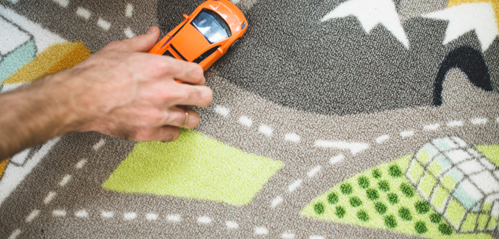 Toy Carpet Map With A Man's Hand Holding A Toy Orange Car