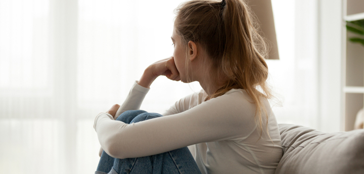 Teenage Girl Sitting On Sofa Looking Out The Window