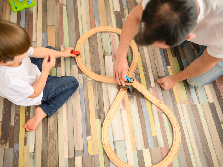 Man And Young Boy Playing With Toy Cars On A Track