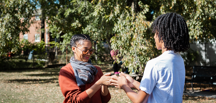 adult woman and teenage boy playing hand slap game outdoors