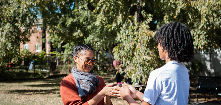 adult woman and teenage boy playing hand slap game outdoors