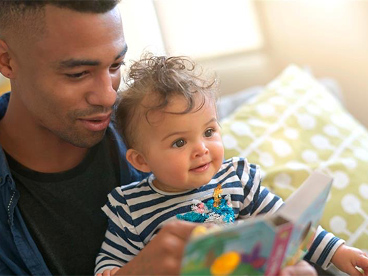 Dad reading a book to his baby who is sitting on his lap