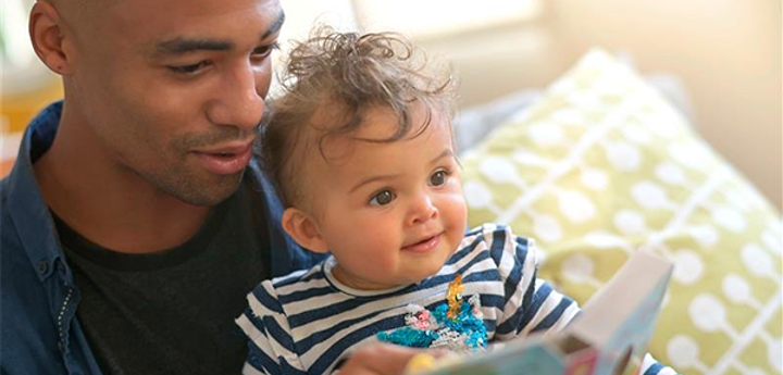 Dad reading a book to his baby who is sitting on his lap