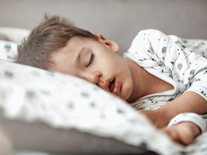 boy sleeping in his bed on his side with his mouth slightly open