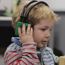 Young boy with headphones on holding a wooden block having a hearing test