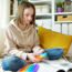 teenage girl on bed, legs crossed playing with fidget toy on bed with ipad and notebook in front of her