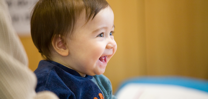 smiling baby sitting down next to adult