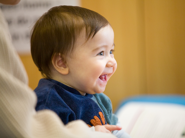 smiling baby sitting down next to adult