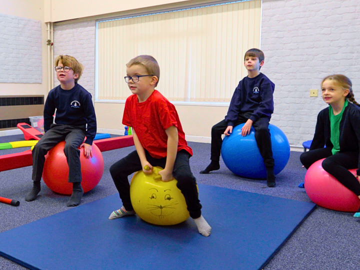 4 Young Children Sitting On Space Hoppers In A Classroom Vibrant